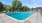 Large sparkling blue pool with a large pool deck and lounge chairs